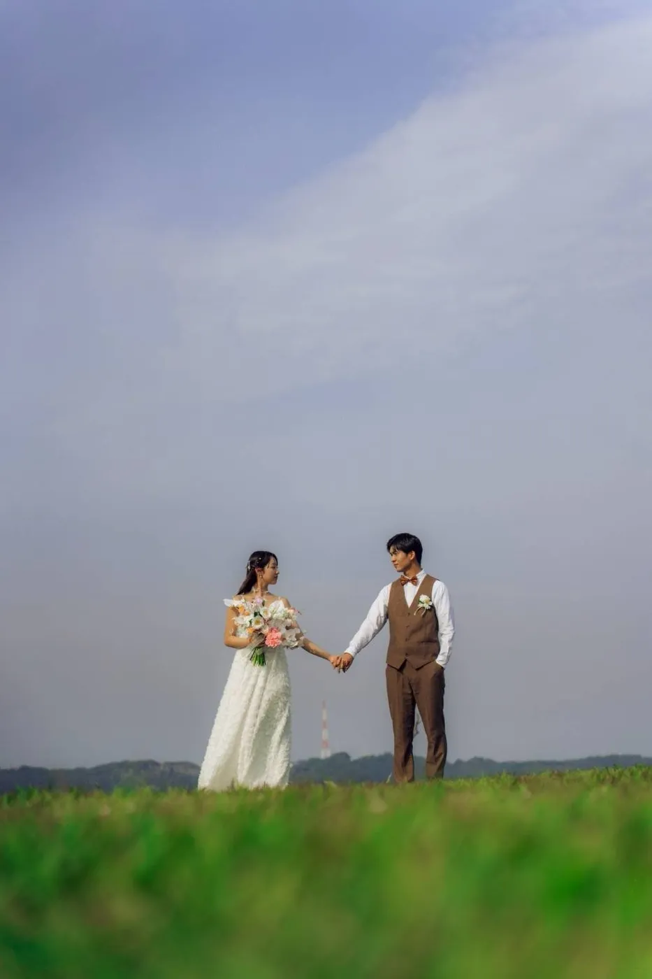 城ヶ島の草原で手をつなぐ新郎新婦